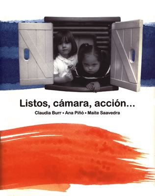 Book cover of Listos, Camara, Accion with a photograph of two children in a window with a swatch of red watercolor paint and blue watercolor paint.